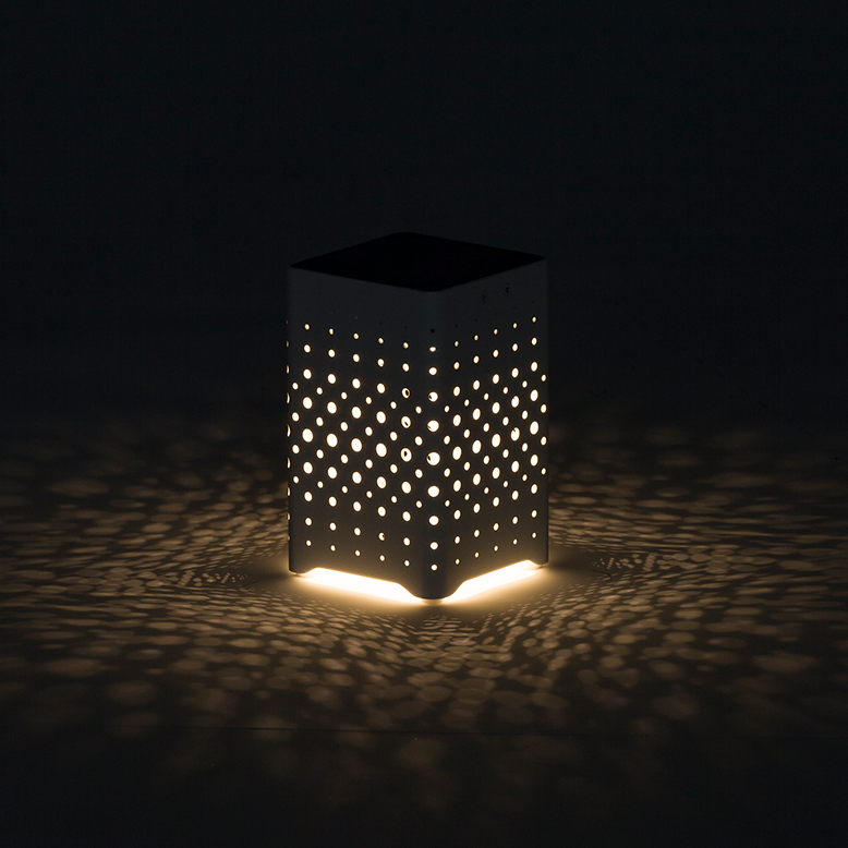 灯りの付いたリヒトビームテーブルライトが暗い空間で地面に光の模様を描いている